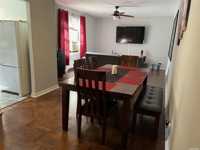 dining space with ceiling fan and dark parquet floors