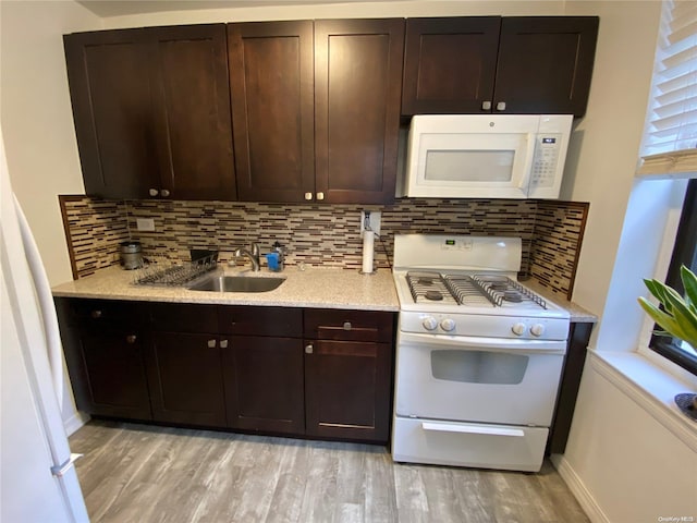 kitchen with sink, backsplash, white appliances, dark brown cabinets, and light wood-type flooring