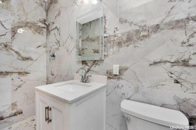 bathroom with vanity, tile walls, and toilet