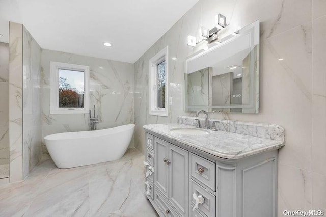 bathroom featuring a washtub, vanity, and tile walls