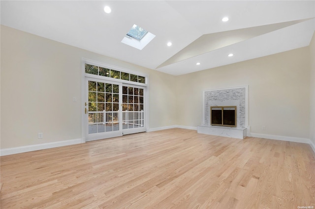 unfurnished living room with light hardwood / wood-style floors and vaulted ceiling with skylight