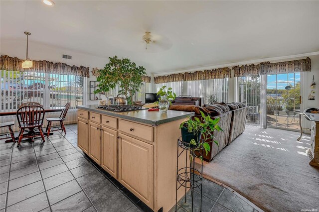 kitchen with ceiling fan, a center island, dark carpet, and stainless steel gas stovetop