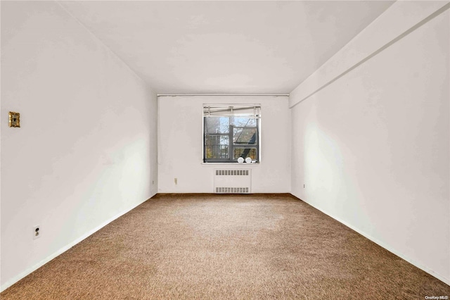 spare room with radiator heating unit and carpet floors