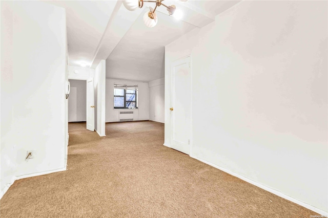 carpeted empty room featuring radiator and a notable chandelier