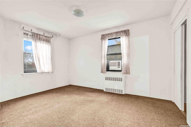 carpeted empty room with a healthy amount of sunlight, radiator, and cooling unit