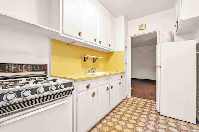 kitchen with white cabinets, stove, white fridge, and sink