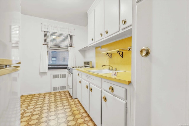 kitchen featuring sink, white cabinets, white range, and radiator heating unit