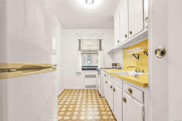 kitchen with white cabinets, sink, radiator heating unit, and white electric stove