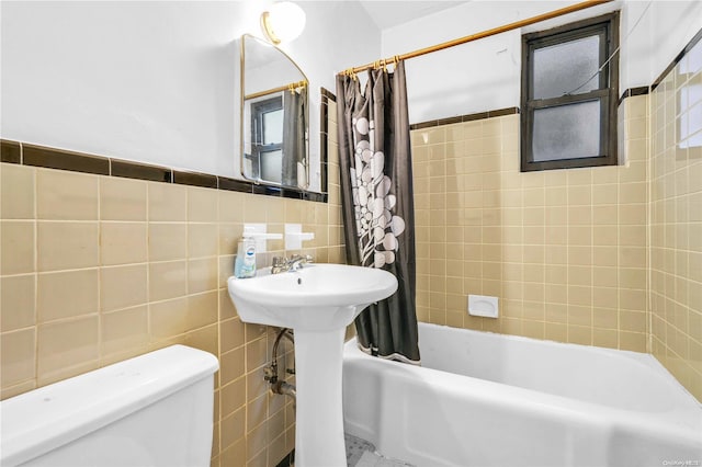 bathroom with toilet, tile walls, and shower / tub combo with curtain