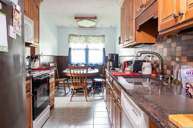 kitchen featuring sink, tile patterned flooring, decorative backsplash, dark stone countertops, and stainless steel appliances