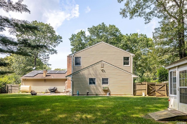 back of house featuring a lawn, solar panels, and a patio area