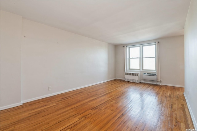 empty room with radiator heating unit and hardwood / wood-style flooring