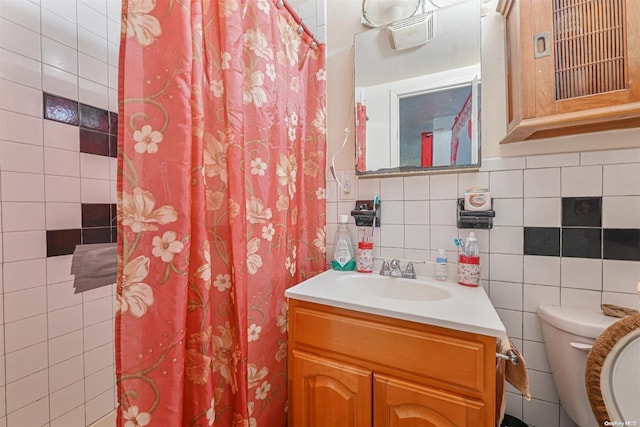 bathroom featuring vanity, toilet, and tile walls