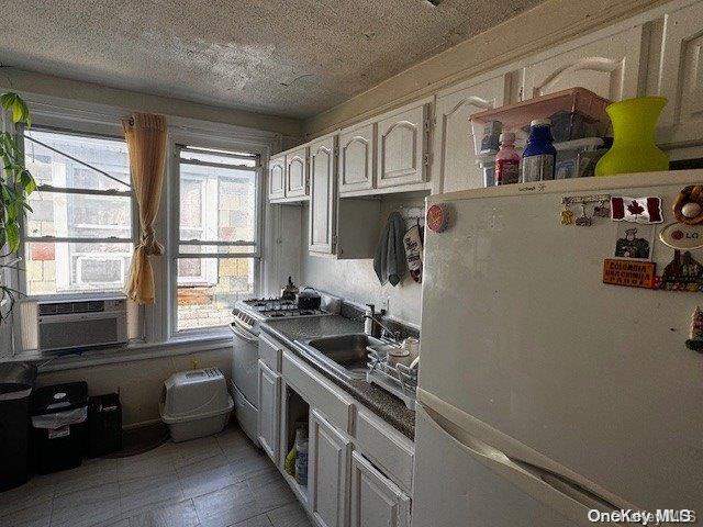 kitchen with sink, cooling unit, white fridge, white cabinets, and stainless steel range with gas stovetop