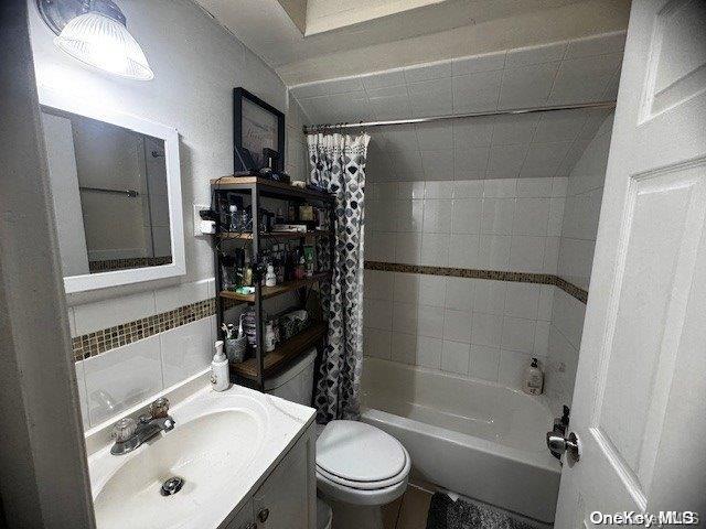 full bathroom featuring shower / tub combo with curtain, vanity, tile walls, and toilet