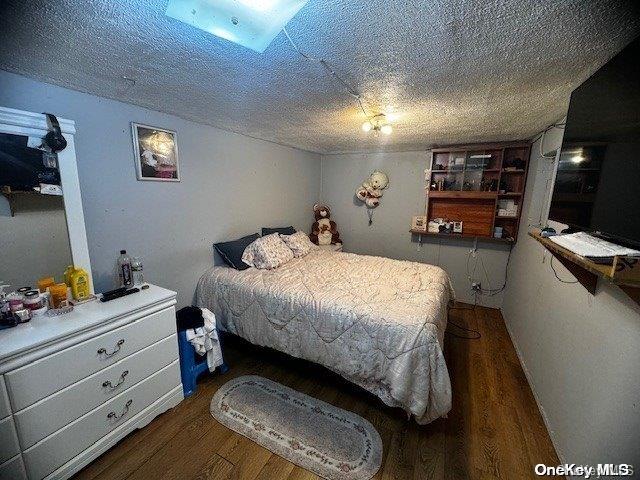 bedroom featuring a textured ceiling and dark hardwood / wood-style floors