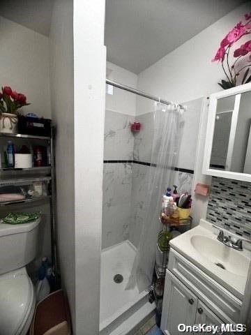 bathroom with decorative backsplash, toilet, vanity, and a shower with shower curtain