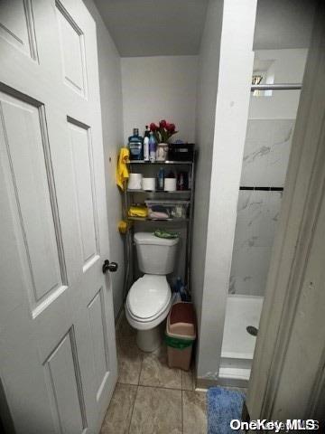 bathroom featuring a shower, tile patterned floors, and toilet