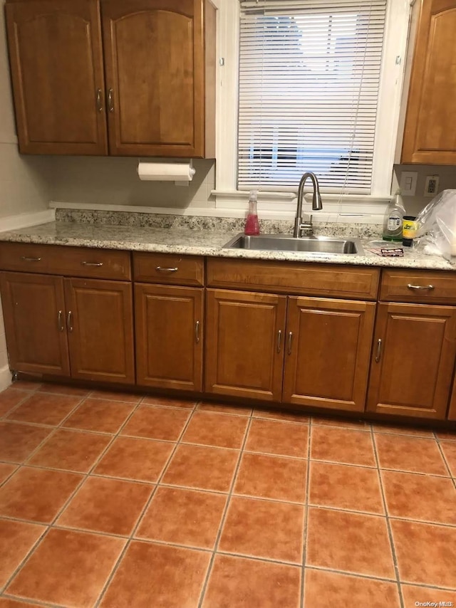 kitchen featuring tile patterned floors, light stone counters, and sink