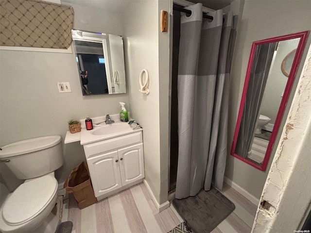 bathroom with a shower with curtain, vanity, wood-type flooring, and toilet