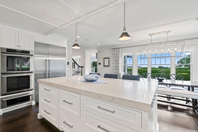 kitchen featuring appliances with stainless steel finishes, decorative light fixtures, white cabinetry, and plenty of natural light