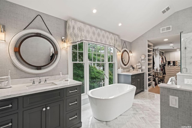 bathroom with a bathing tub, vanity, parquet floors, and vaulted ceiling