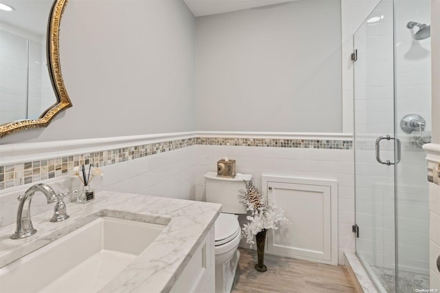 bathroom with vanity, toilet, walk in shower, and tile walls