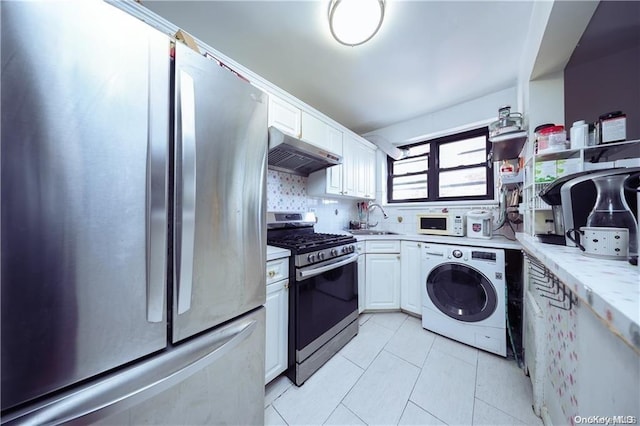 kitchen with light stone counters, stainless steel appliances, sink, washer / dryer, and white cabinetry