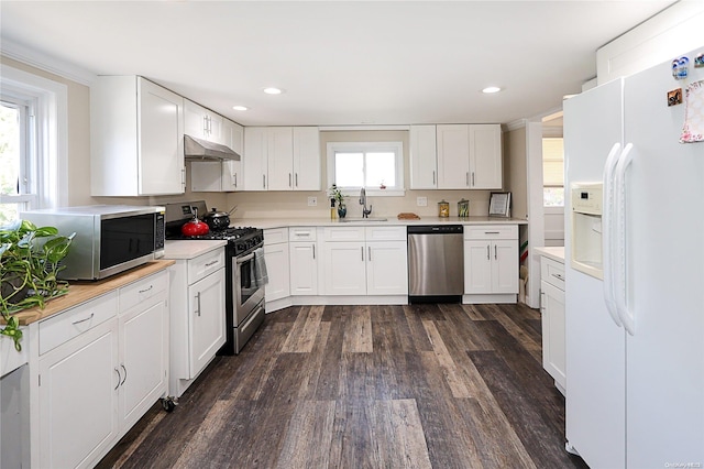 kitchen with appliances with stainless steel finishes, white cabinetry, a healthy amount of sunlight, and sink