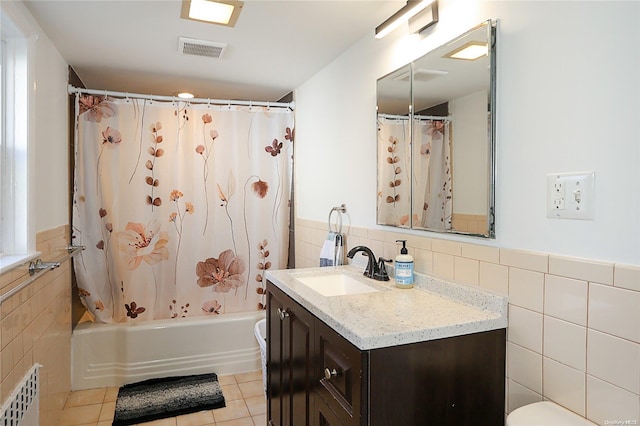 bathroom featuring radiator heating unit, tile patterned floors, shower / tub combo with curtain, vanity, and tile walls