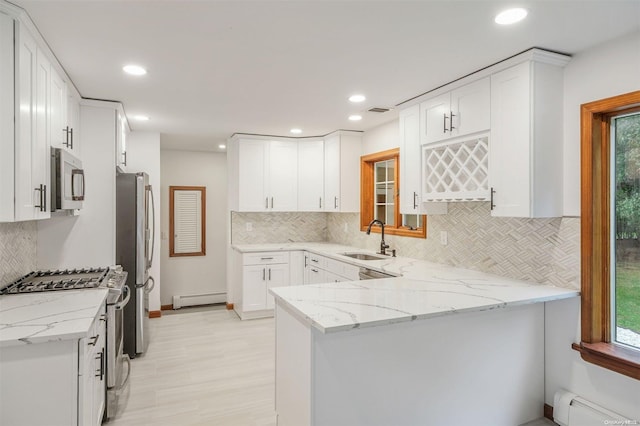 kitchen with white cabinets, kitchen peninsula, light stone countertops, and stainless steel appliances