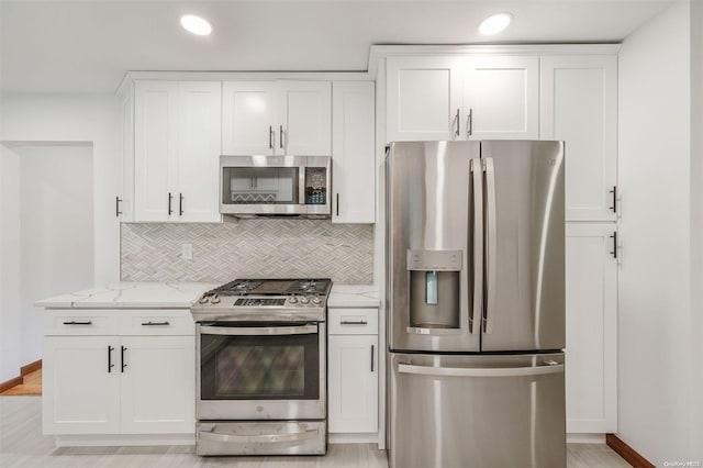 kitchen with light hardwood / wood-style flooring, light stone countertops, tasteful backsplash, white cabinetry, and stainless steel appliances