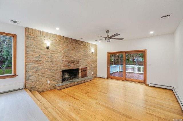 unfurnished living room featuring a fireplace, ceiling fan, light hardwood / wood-style flooring, and a baseboard heating unit