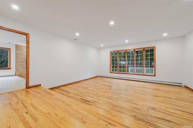 empty room featuring a healthy amount of sunlight, light hardwood / wood-style floors, and a baseboard radiator