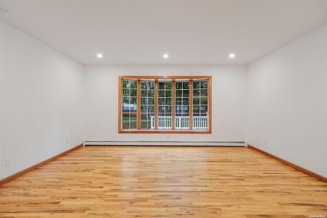 empty room with light hardwood / wood-style floors and a baseboard heating unit