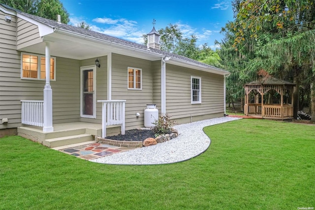 back of property featuring a gazebo and a yard