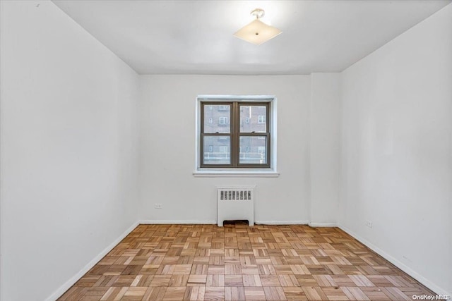 unfurnished room with radiator heating unit and light parquet flooring