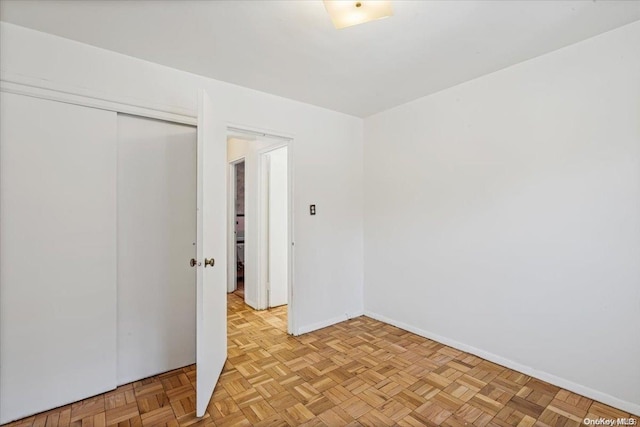 unfurnished bedroom with light parquet flooring and a closet