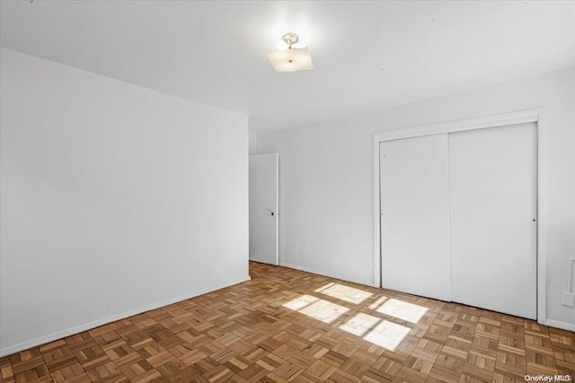 unfurnished bedroom with parquet floors and a closet