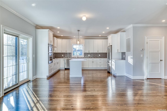 kitchen with appliances with stainless steel finishes, dark wood-type flooring, a center island, white cabinetry, and hanging light fixtures