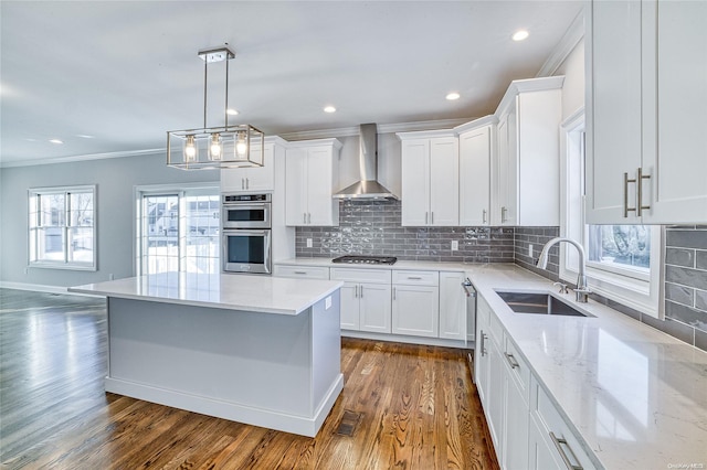 kitchen featuring wall chimney exhaust hood, white cabinetry, sink, and stainless steel appliances