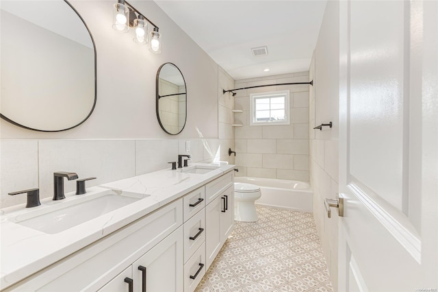 full bathroom with toilet, vanity, tile walls, and tiled shower / bath