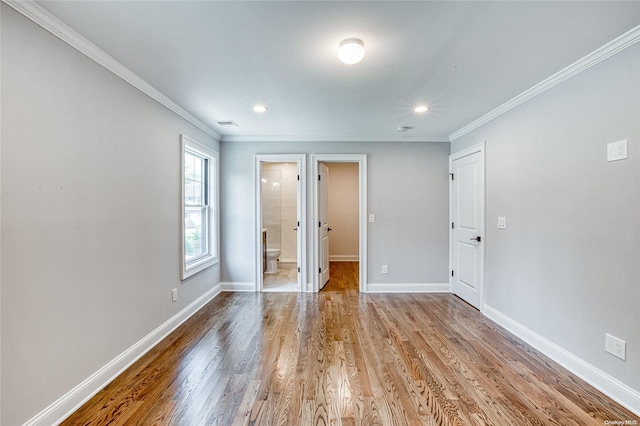 unfurnished bedroom with light wood-type flooring, crown molding, and connected bathroom