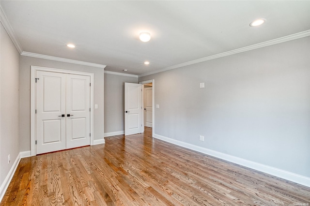 unfurnished bedroom featuring light wood-type flooring, ornamental molding, and a closet