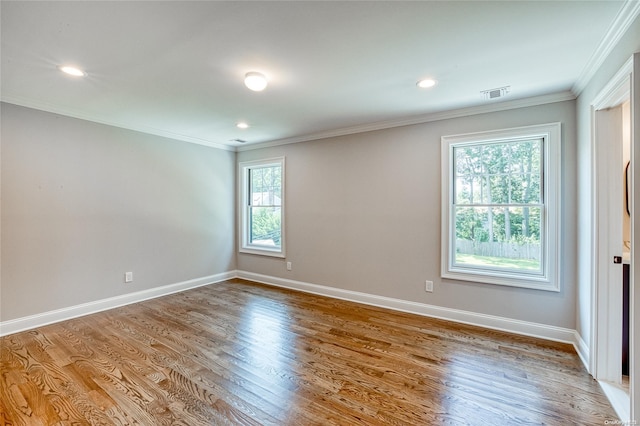 spare room with crown molding, plenty of natural light, and hardwood / wood-style flooring