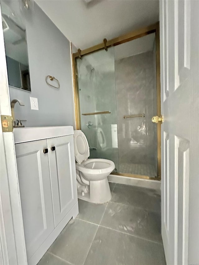 bathroom featuring vanity, a shower stall, toilet, and tile patterned floors