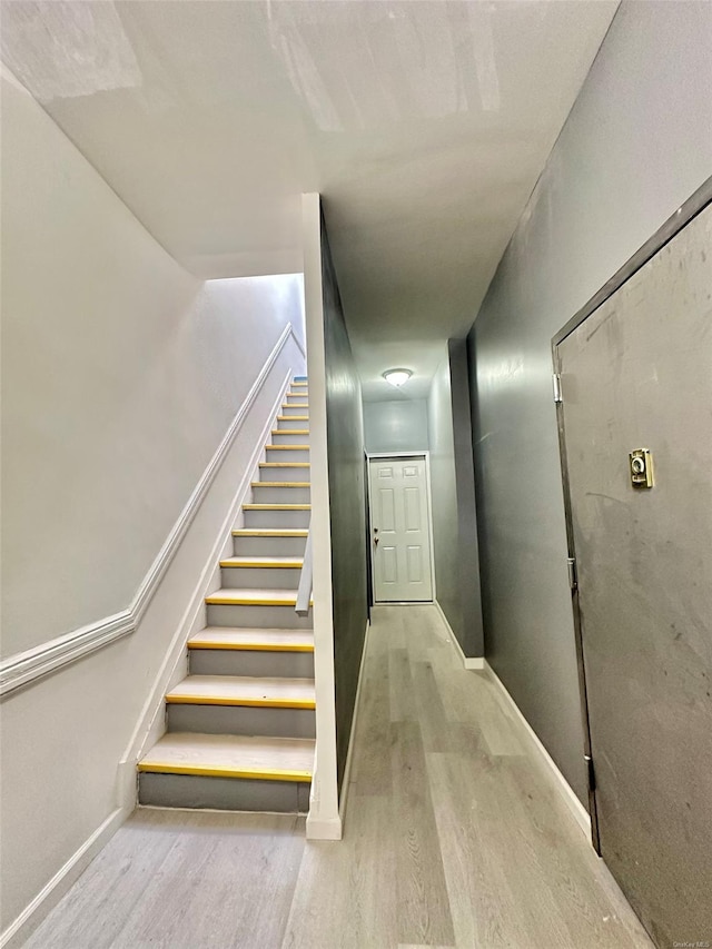 stairway with baseboards and wood finished floors