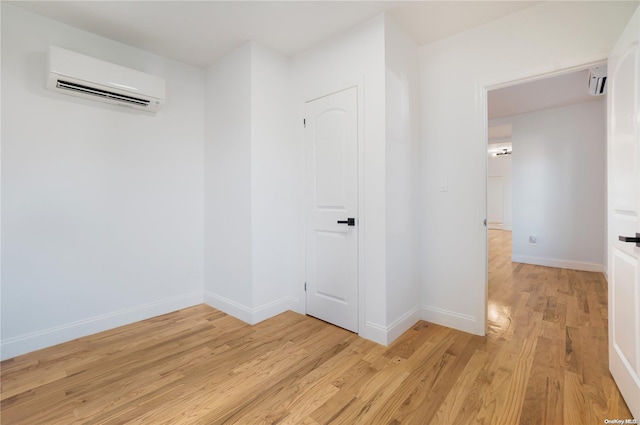 hall featuring light wood-type flooring and an AC wall unit