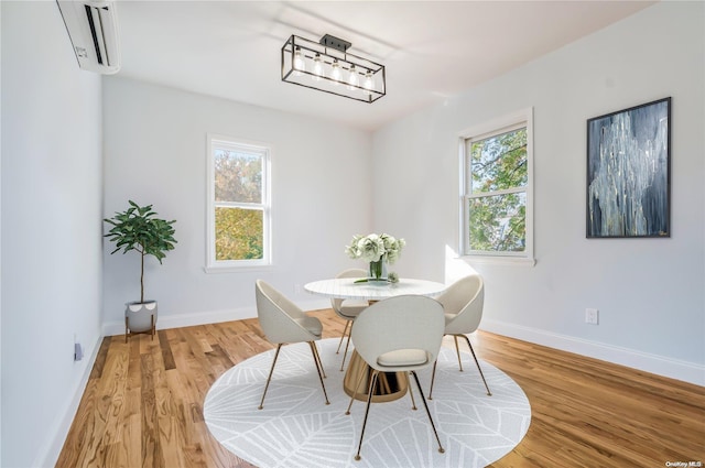 dining room featuring a wall mounted air conditioner, light hardwood / wood-style flooring, and a healthy amount of sunlight