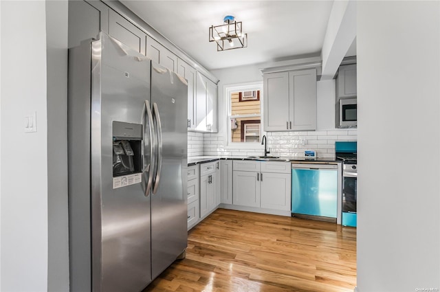 kitchen featuring decorative backsplash, sink, stainless steel appliances, and light hardwood / wood-style flooring